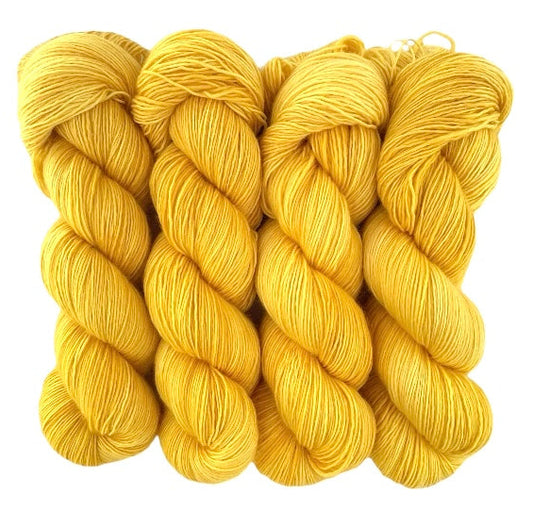 Four skeins of extrafine superwash sock weight merino wool, hand dyed yellow.