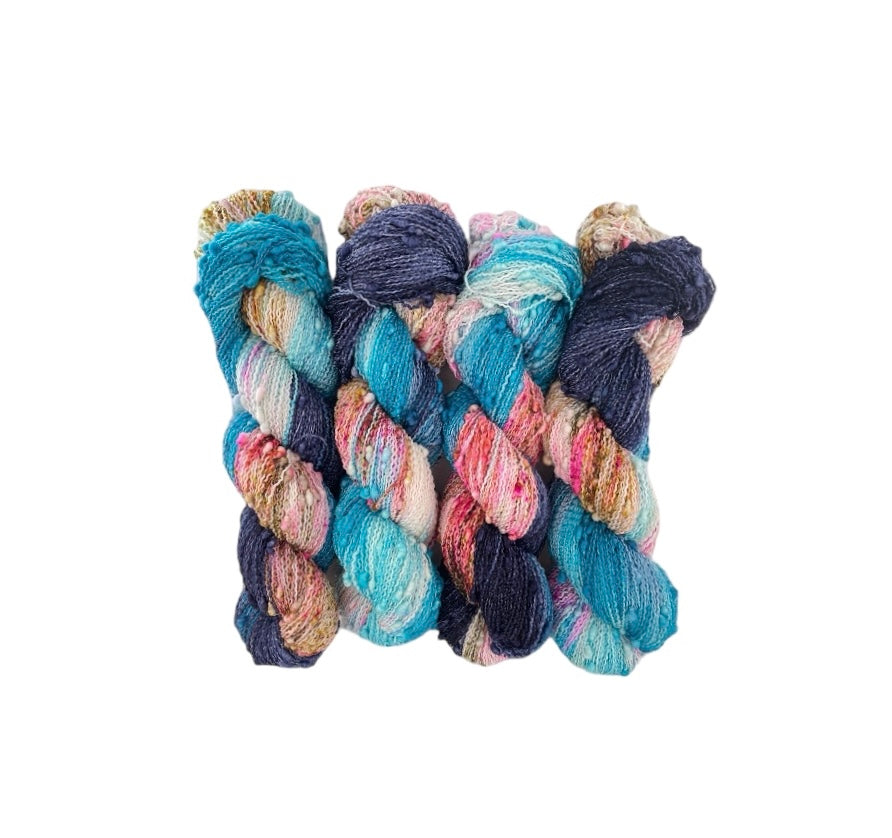 EVENING MAGIC yarn offers a unique blend of merino and nylon for added durability. The textured slub design in navy, turquoise, pink, and white adds depth and dimension to any project. Each 100g skein is perfect for lightweight, yet sturdy, fingering weight projects.