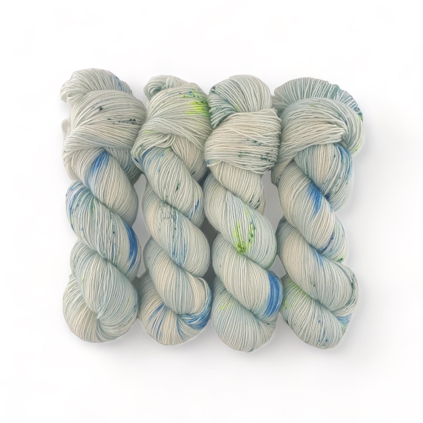 Enhance your crafting with NEW DAY hand-dyed yarn. Made from 100% extrafine superwash merino wool, this fingering/sock weight singles yarn boasts a single ply light blue base with intricate green and blue speckles. Elevate your projects with its unique and high-quality design.