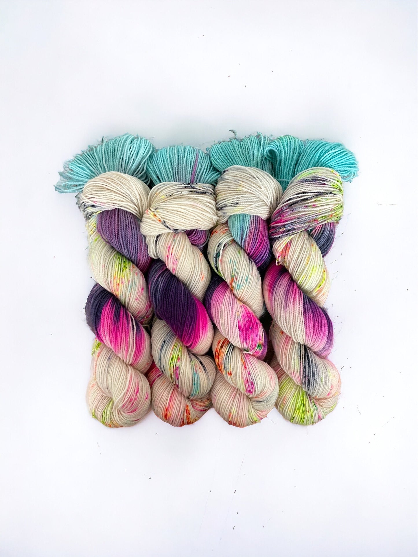 Expertly dyed in cream with pops of turquoise, purple, and pink, our JOY Hand Dyed Yarn is made from luxurious British Blue Faced Leicester wool and durable nylon. Perfect for fingering and sock weight projects, its speckled design adds a unique touch to your handcrafted pieces.